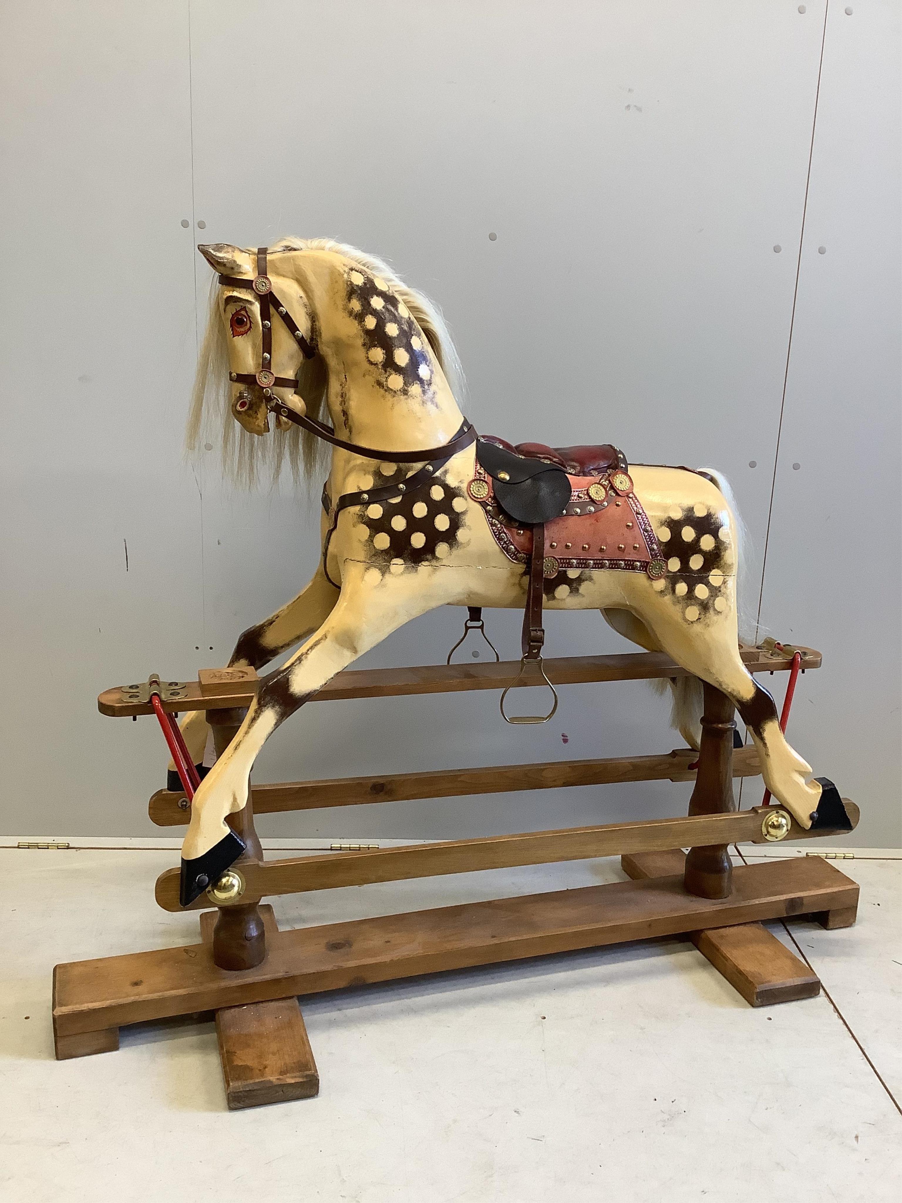 A large carved wooden rocking horse on a pine stand, the body painted in dapple grey, with glass eyes and upholstered leather saddle, height to the top of the head 130cm, length of base 152cm. Condition - fair to good.